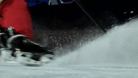 El-Primer-Plano-Del-Disco-Está-Sobre-El-Hielo-Y,-En-Cámara-Lenta,-El-Jugador-De-Hockey-Se-Detiene-Y-La-Nieve-Vuela-Hacia-La-Cámara-Y-Toma-El-Palo-Del-Disco.